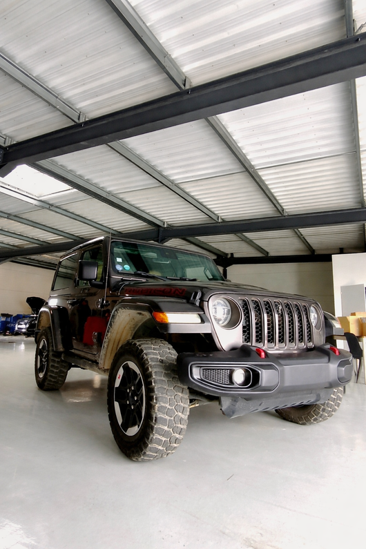 Jeep Wrangler noire dans un garage couvert, vue de l'avant gauche.