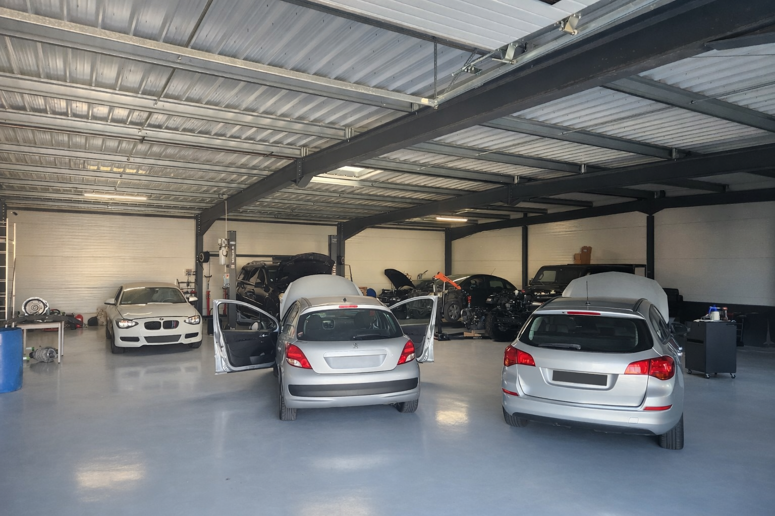 Garage de stationnement couvert avec plusieurs voitures garées sous un toit métallique.