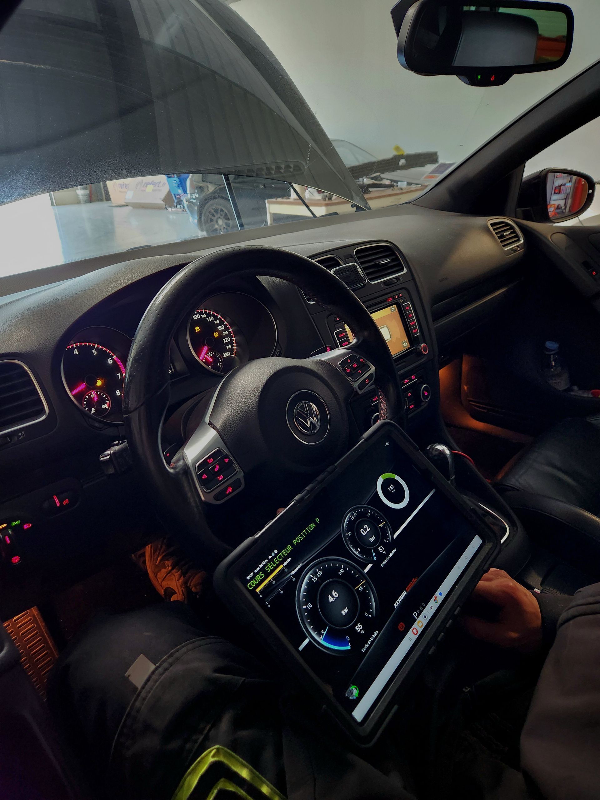 Intérieur de voiture avec tableau de bord, volant, console centrale et vue à travers le pare-brise éclairés.