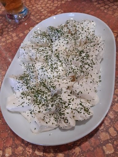 Un plato blanco cubierto con salsa blanca y perejil.