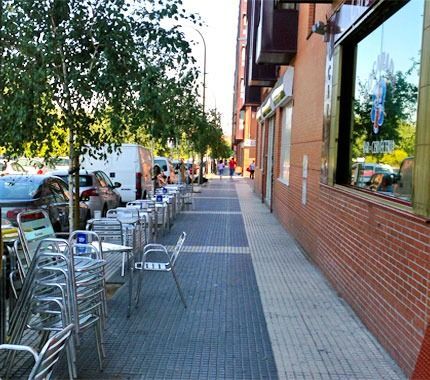 Una fila de mesas y sillas en una acera junto a un edificio de ladrillos.