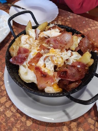Una sartén de comida con huevos y tocino en un plato sobre una mesa.