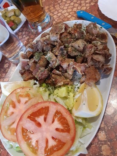 Un plato de comida con tomates, lechuga y limón sobre una mesa.