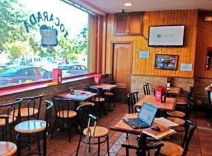 Un restaurante con mesas y sillas y una computadora portátil sobre una mesa.