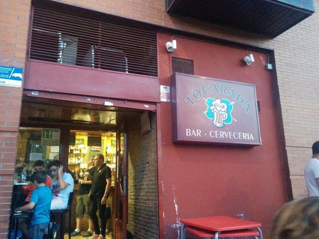 Un grupo de personas está parado afuera de un bar llamado Tocamada.