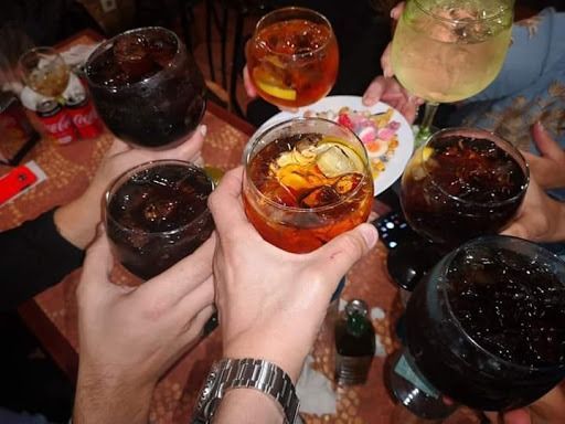 Un grupo de personas está brindando con bebidas, incluida Coca Cola.