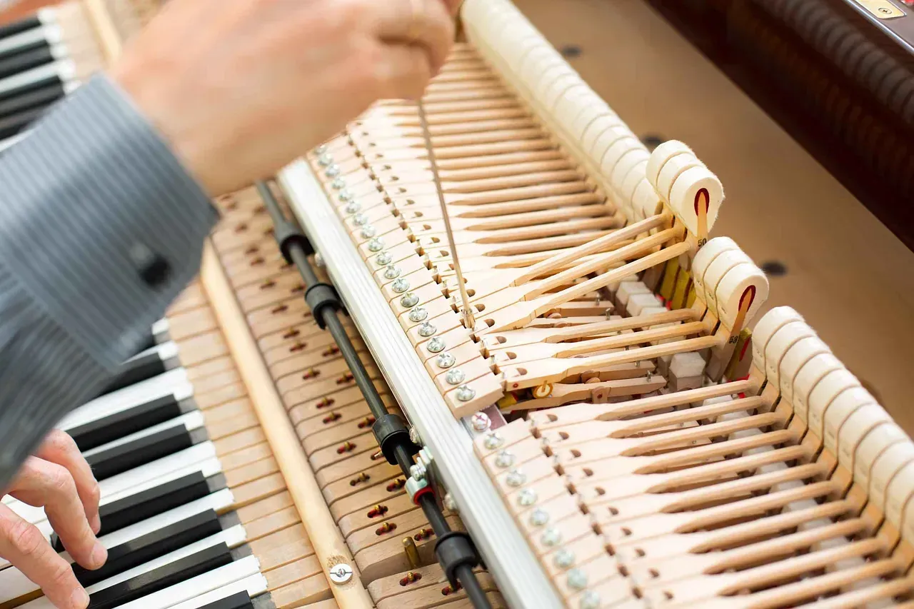 Un hombre está trabajando en el interior de un piano.
