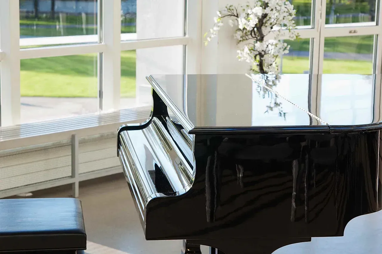 Un piano está sentado frente a una ventana en una habitación.