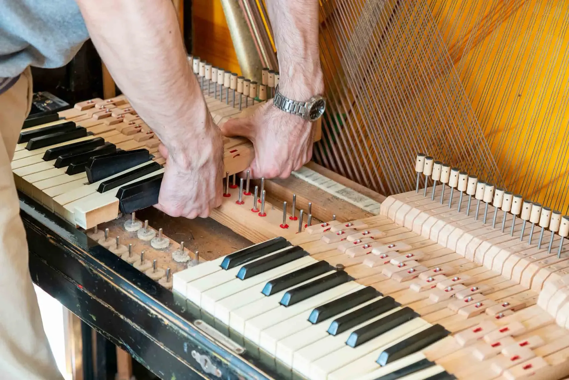 Un hombre está reparando un piano con sus manos.