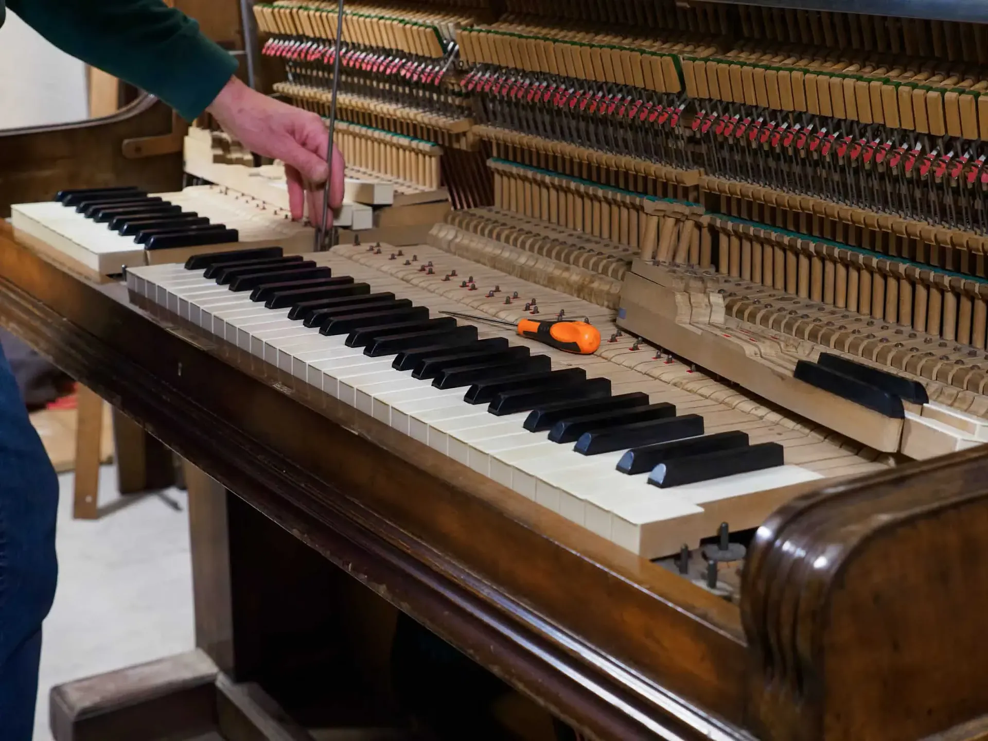 Una persona está trabajando en un teclado de piano con un destornillador.