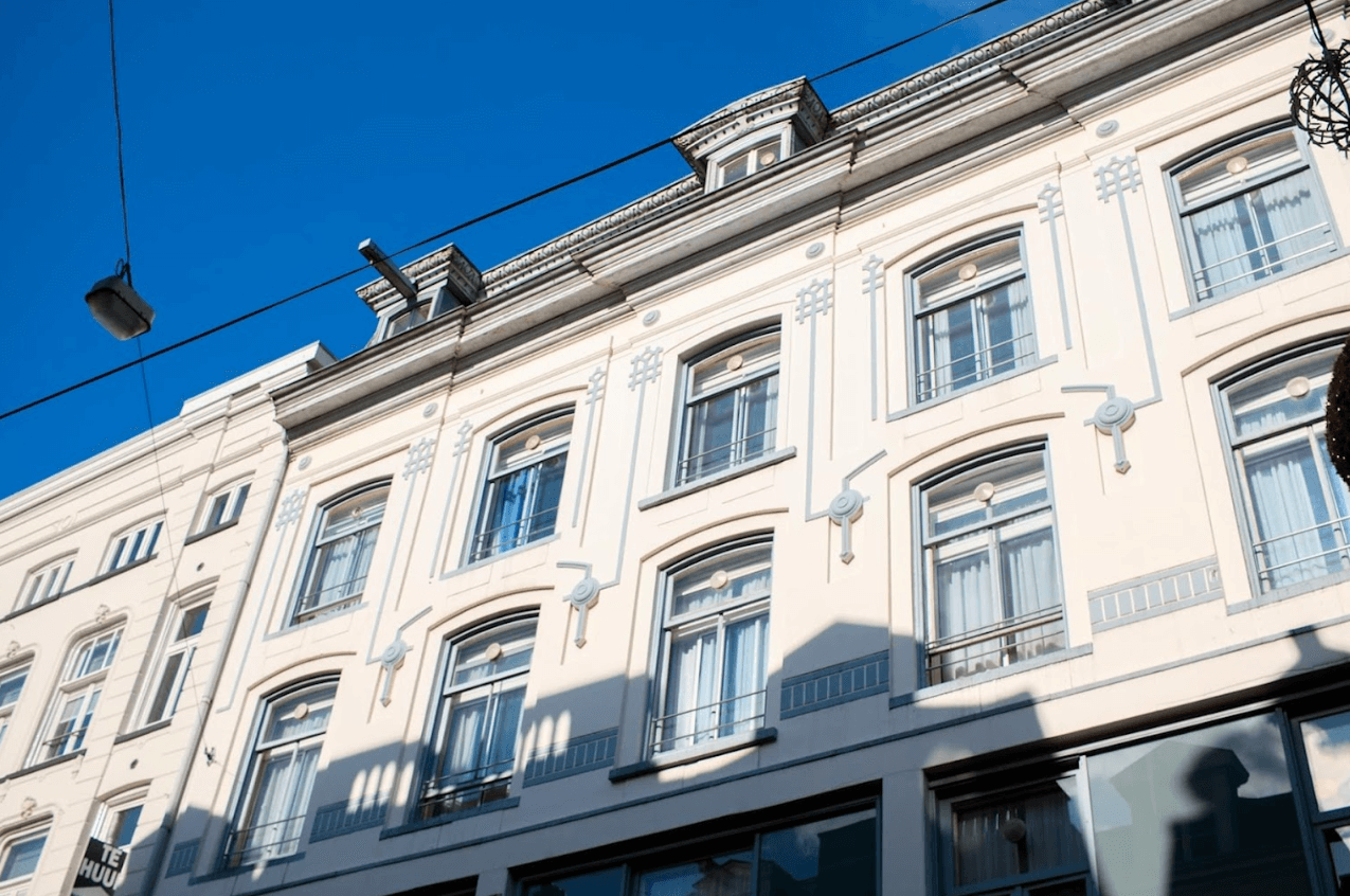 White multi-story building façade with ornate windows against a bright blue sky