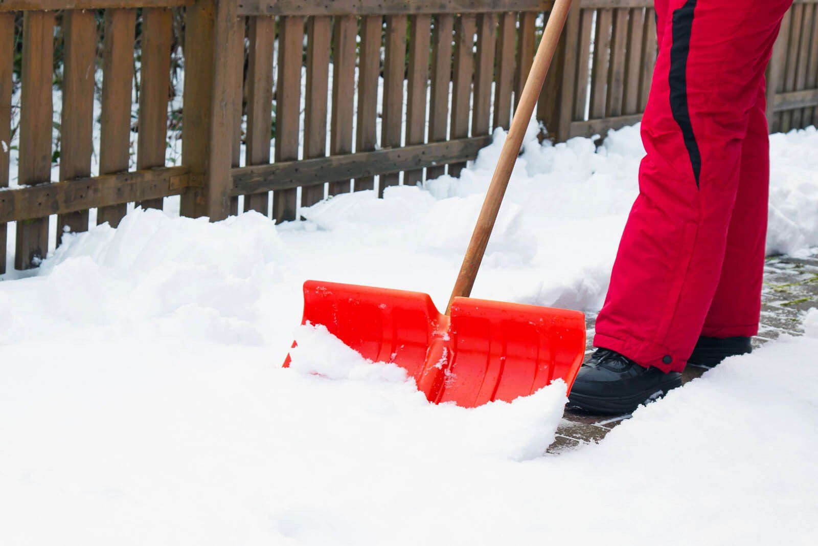 Spécialiste réalisant un déneigement à l'aide d'une pelle rouge