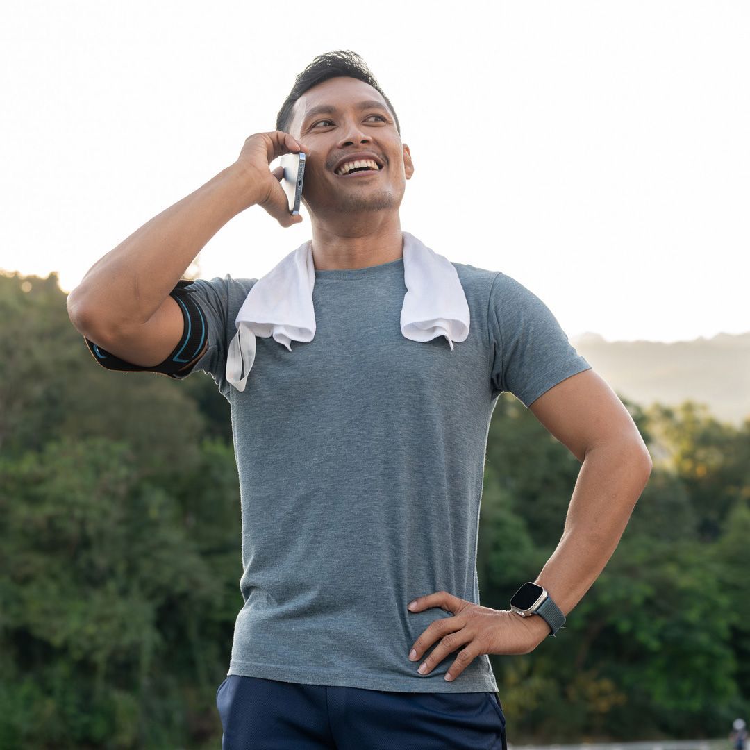 Un hombre está sentado en el suelo en un gimnasio mirando su teléfono celular.