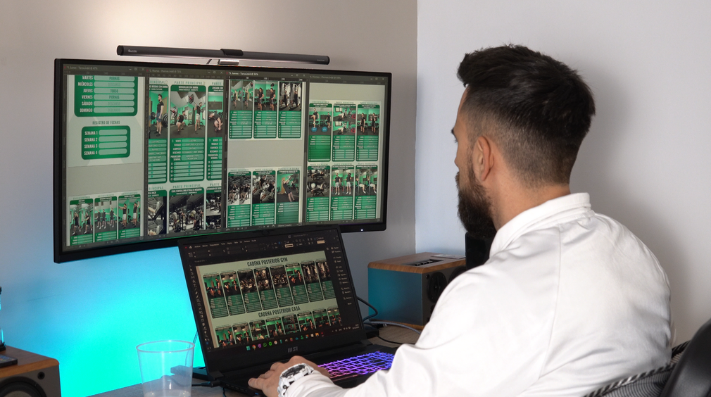 Un hombre está sentado en un escritorio frente a dos monitores de computadora.