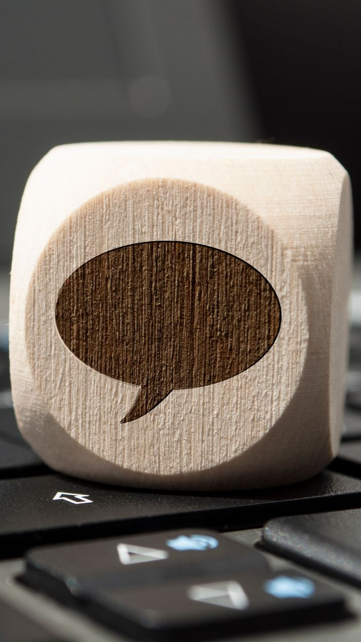 Dé en bois avec bulle de dialogue sur un clavier d'ordinateur portable.