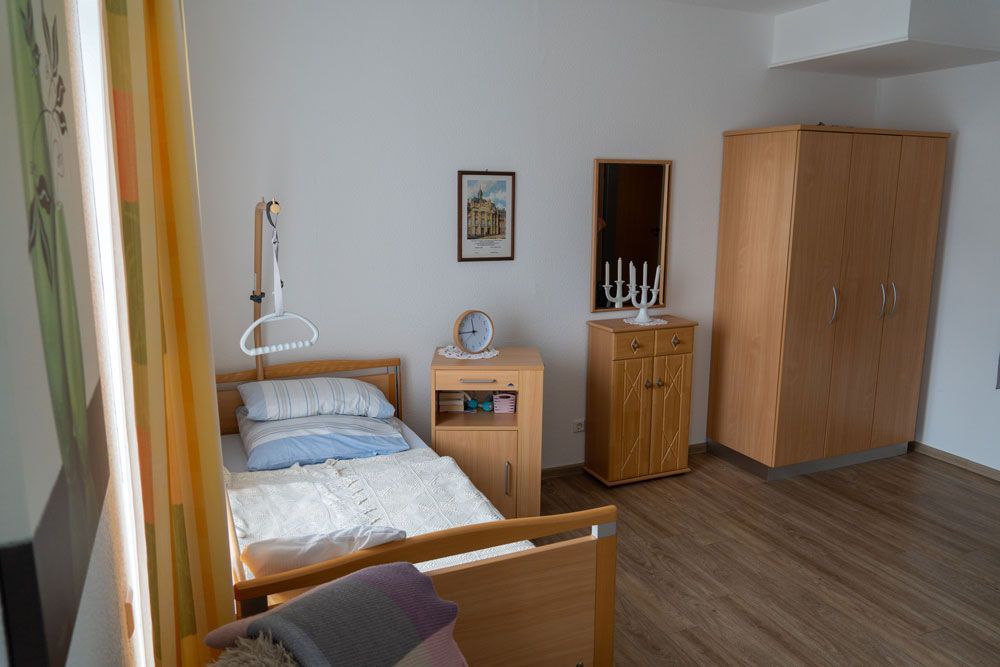 Kleines Schlafzimmer mit Einzelbett, Kleiderschrank, Nachttisch und Holzboden.