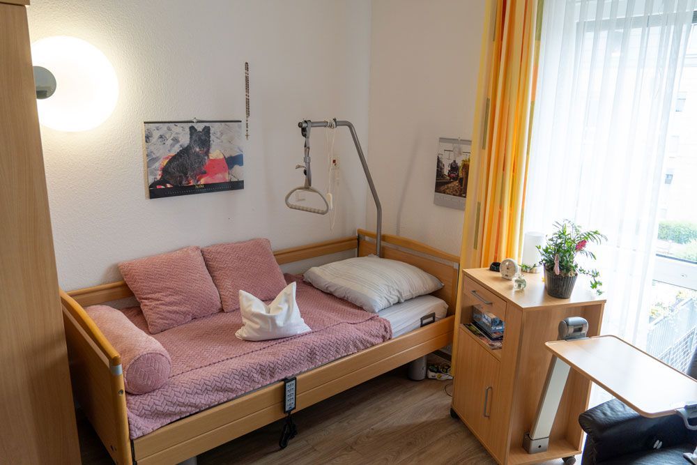 Gemütliches Schlafzimmer mit hölzernem Tagesbett, rosa Bettwäsche und einem hellen Fenster mit transparenten Vorhängen
