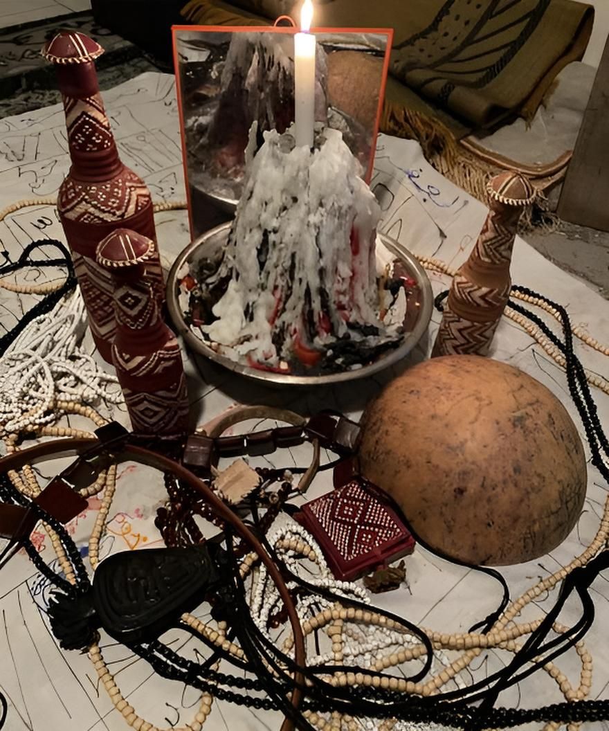 Rituel à la lueur des bougies : bougie dans un plat en métal, objets environnants, perles, calebasses, petites bouteilles sur un tissu blanc.