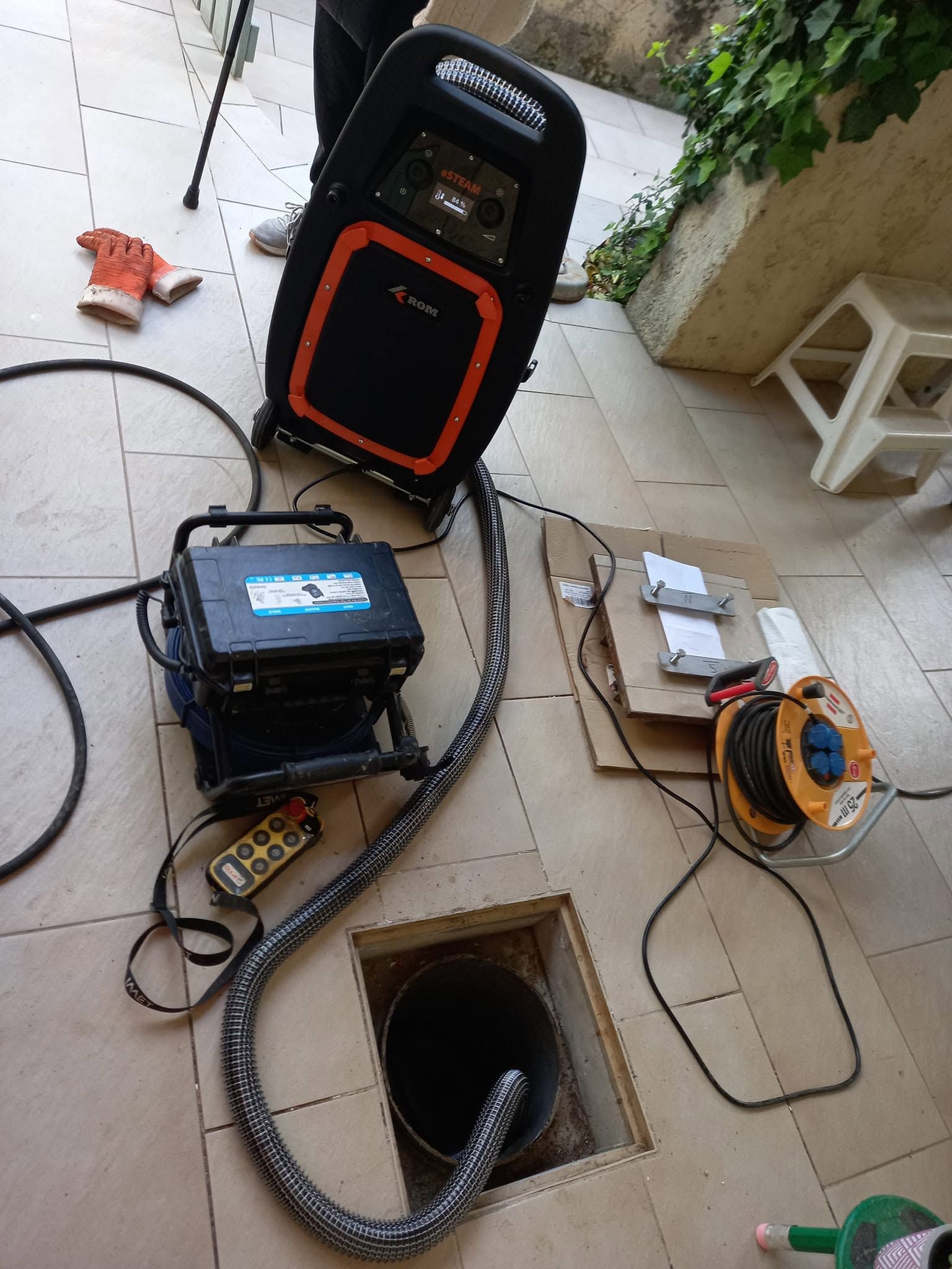 Équipements et câbles installés sur une terrasse à côté d'un regard d'égout ou d'un puits de service ouvert.