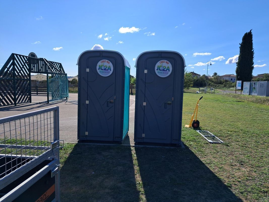 Deux toilettes portables sur un champ sous un ciel d'un bleu éclatant