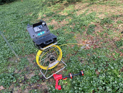 Dispositif robotisé à cadre jaune et foreuse rouge sur l'herbe dans une zone boisée