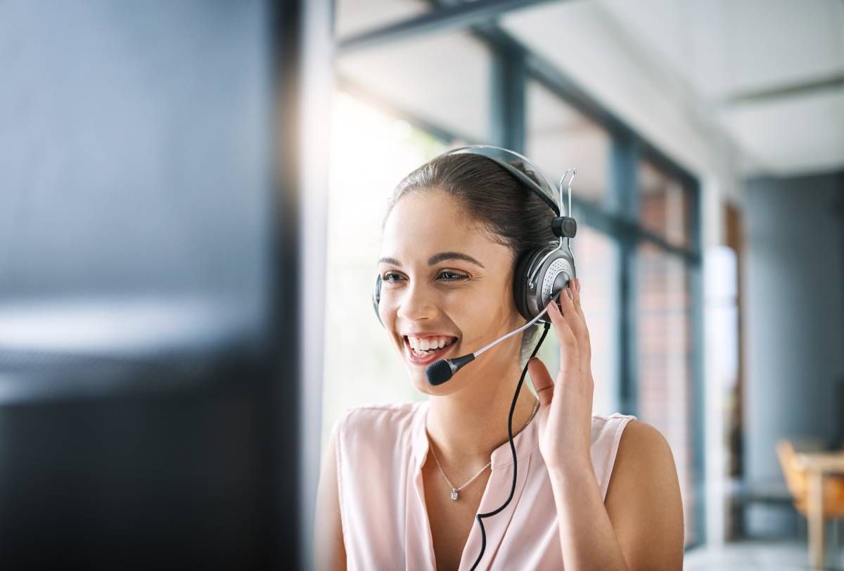 A woman wearing a headset is sitting in front of a computer.