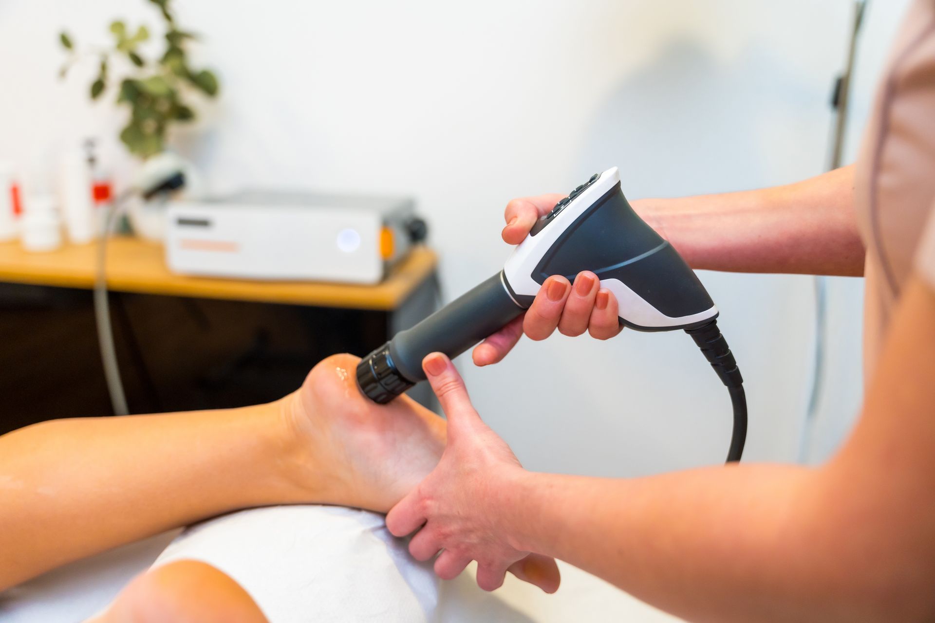 Therapeut wendet Stosswellentherapie am Fuss eines Patienten an.