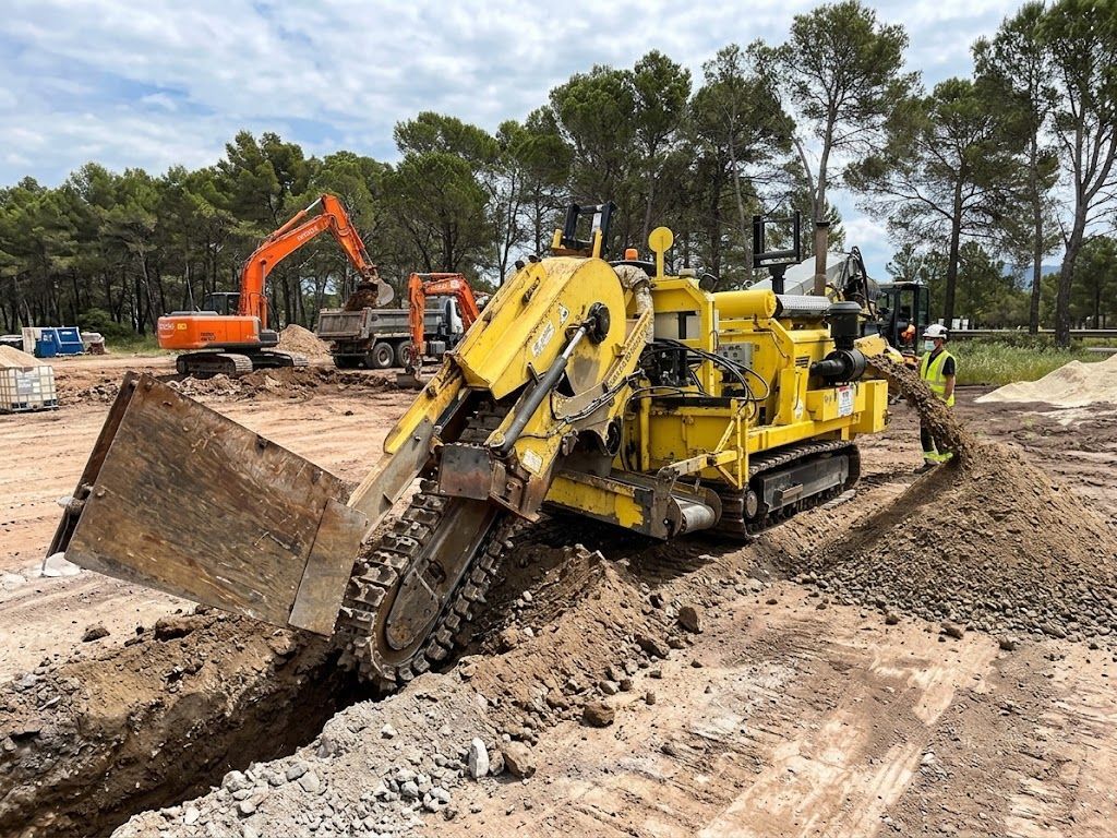 Une trancheuse jaune creusant une tranchée profonde sur un chantier de construction