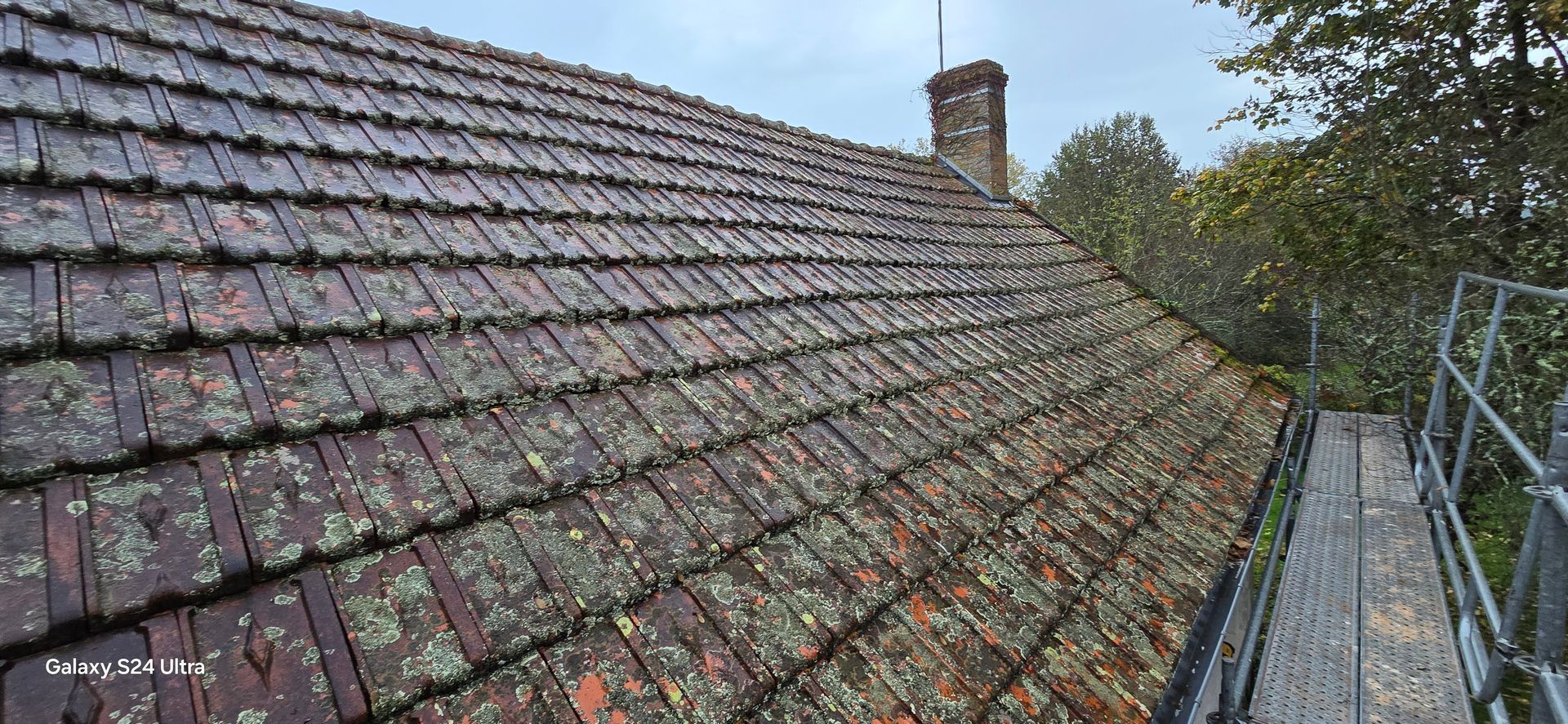 Un toit de tuiles usé et recouvert de mousse.
