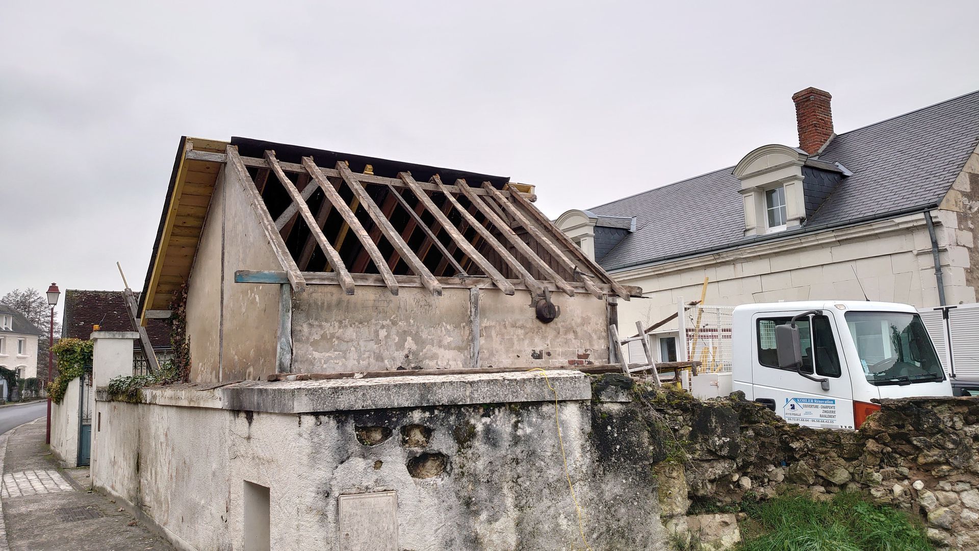 Petit bâtiment aux poutres de toit apparentes, en cours de rénovation.