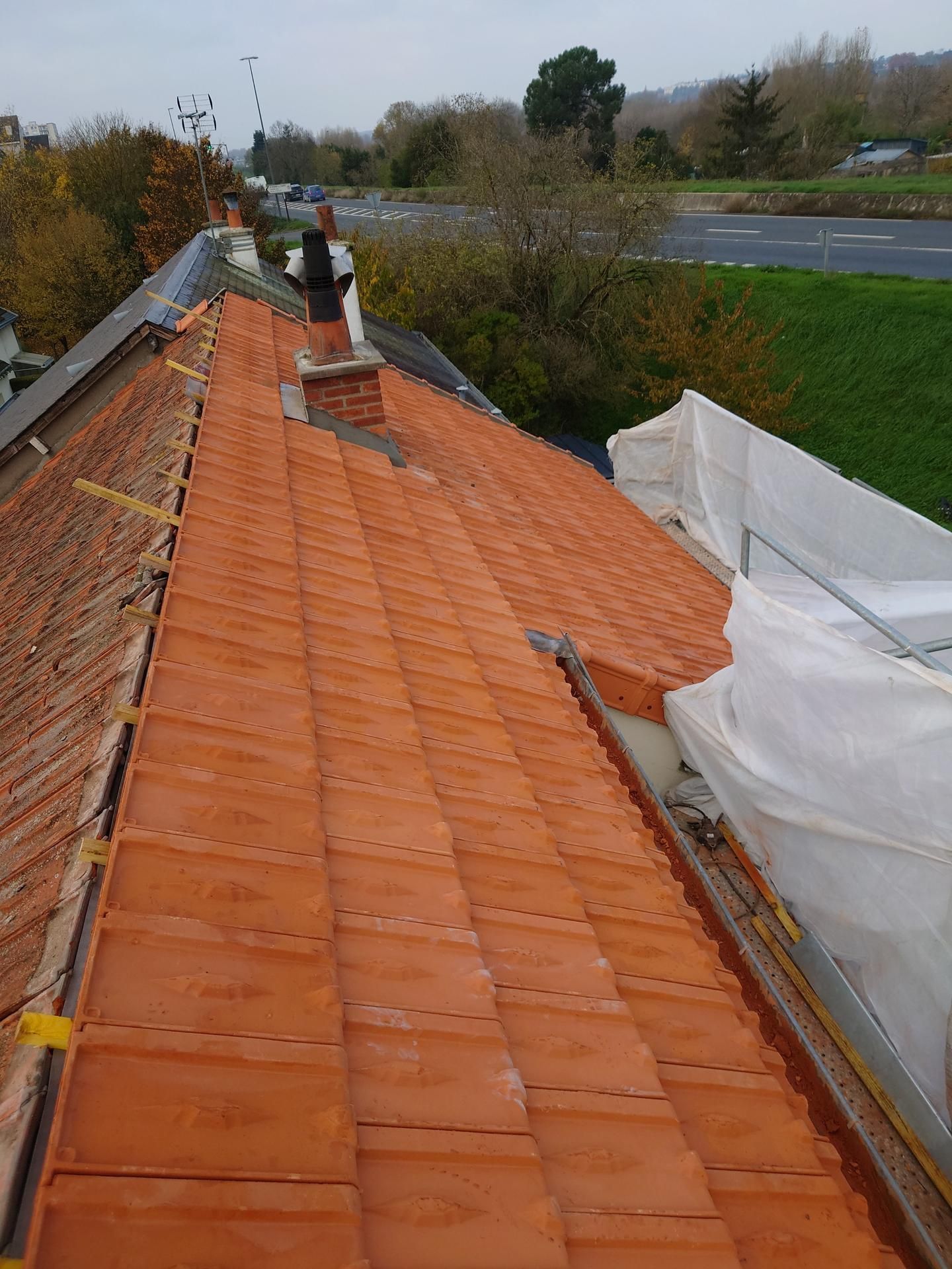 Un toit de tuiles rouges en cours de nettoyage.