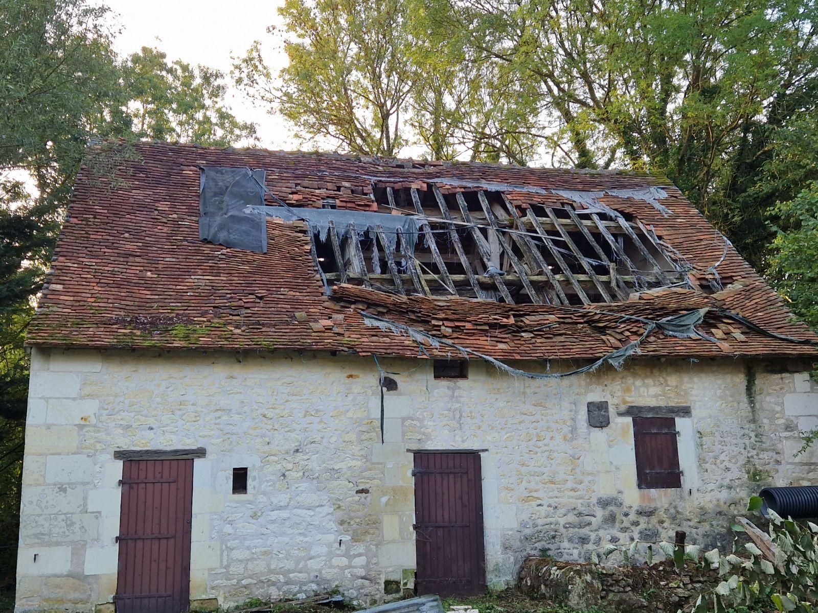 Maison endommagée avec un toit effondré et des tuiles rouges.