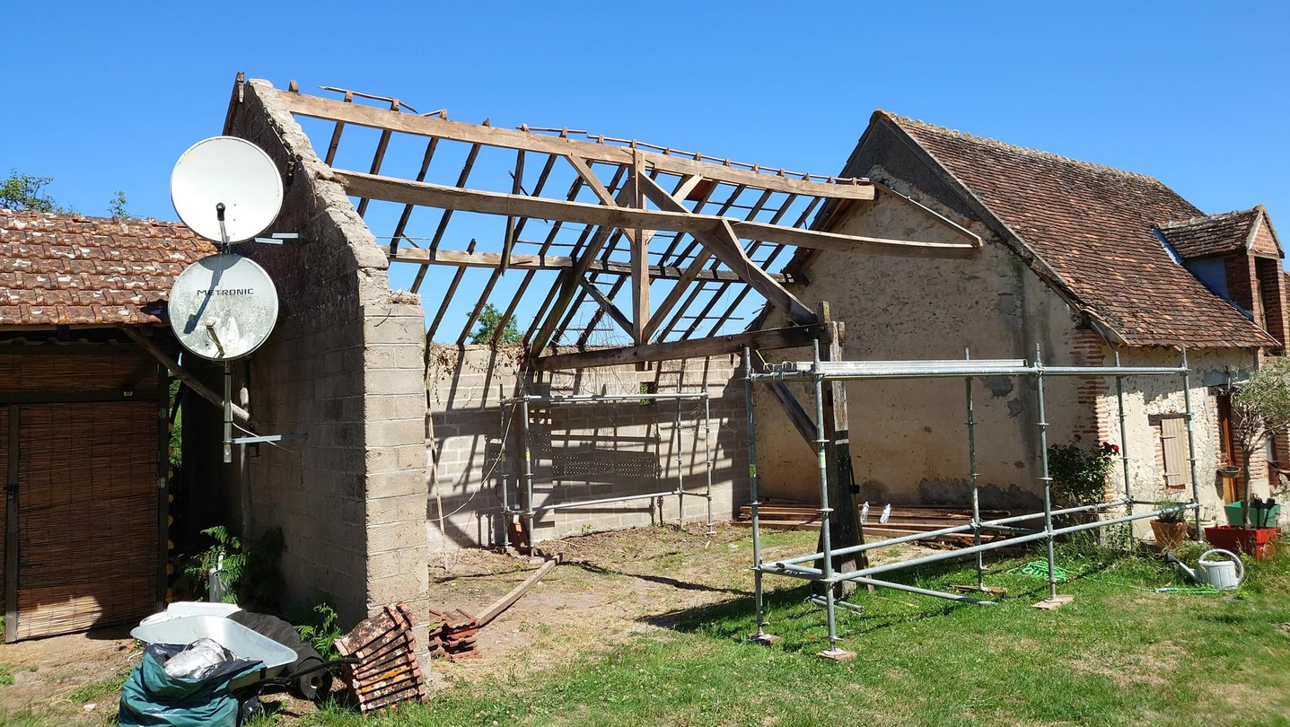 Grange en cours de réfection, charpente apparente et toiture partielle.