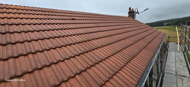 Un toit de tuiles en terre cuite avec une cheminée et une gouttière.