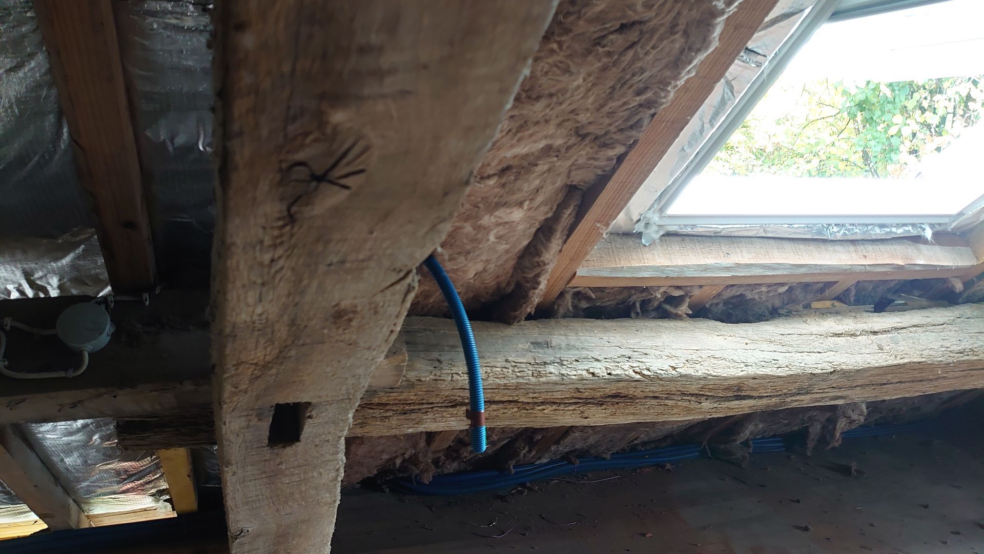 Des panneaux isolants bruns installés entre les chevrons en bois d'une toiture.