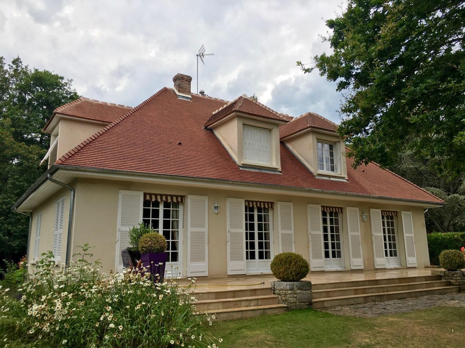 Maison beige avec un toit de tuiles rouges.