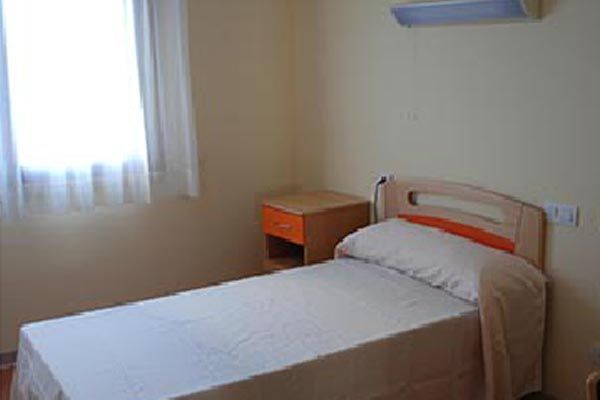 Un dormitorio con una cama individual, mesita de noche y ventana.