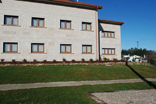 Un gran edificio con muchas ventanas está situado en la cima de una colina cubierta de hierba.