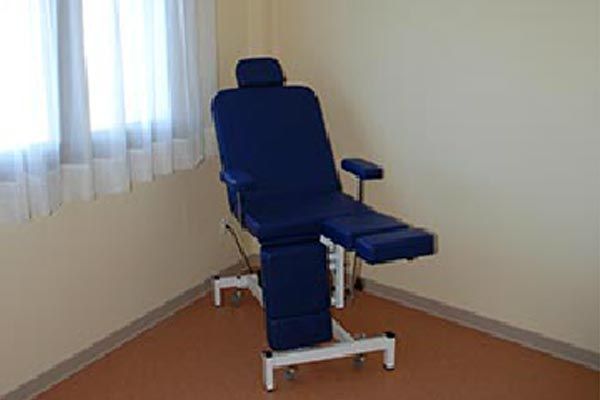 Una silla azul está en un rincón de una habitación al lado de una ventana.