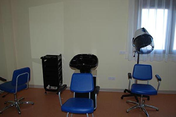 Una habitación con sillas azules, un lavabo y un secador de pelo.