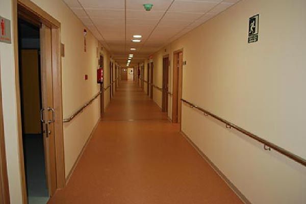 Un pasillo largo con muchas puertas y un extintor de incendios en la pared.