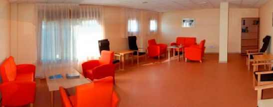 Una gran sala con sillas y mesas de color naranja.