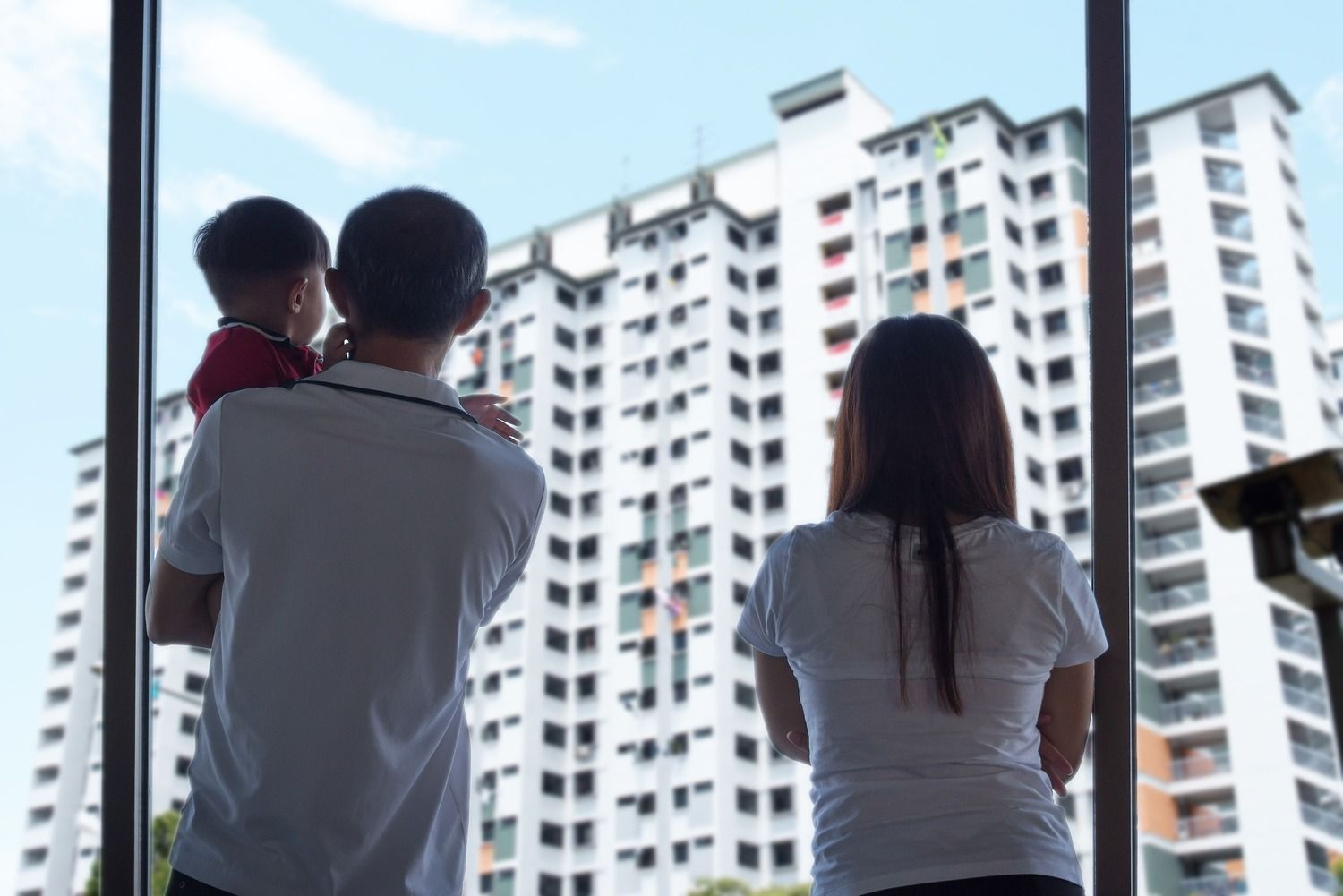 Una familia mira desde una ventana un edificio alto.