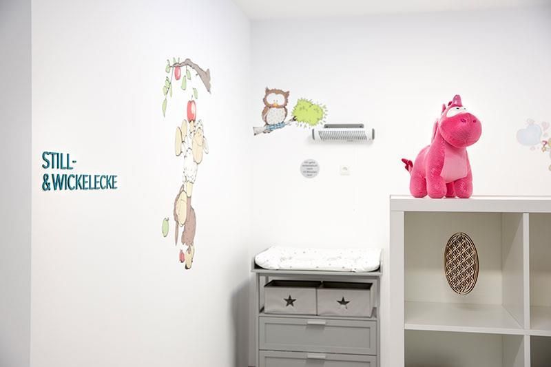 Ein rosa Stofftier sitzt auf einem Regal in einem Raum mit einem Schild, auf dem steht: „Still“