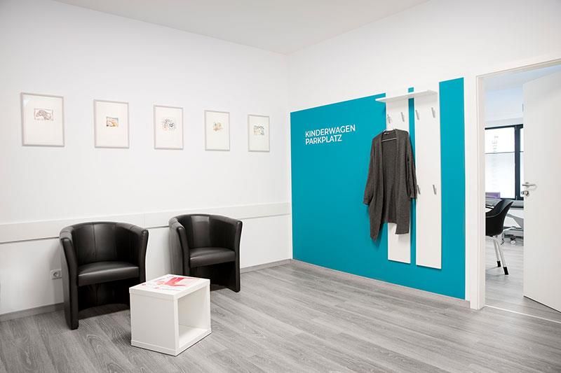 Ein Wartezimmer mit schwarzen Stühlen und einer blauen Wand