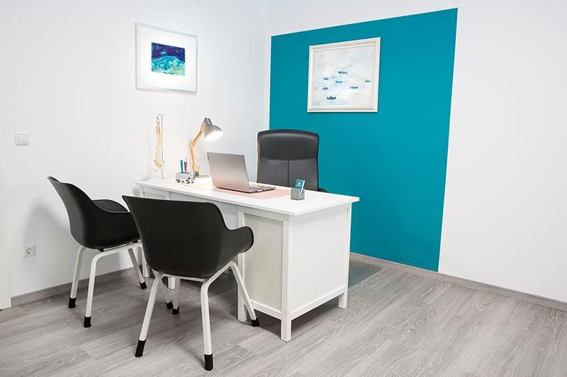 Ein weißer Schreibtisch mit zwei Stühlen und einem Laptop darauf