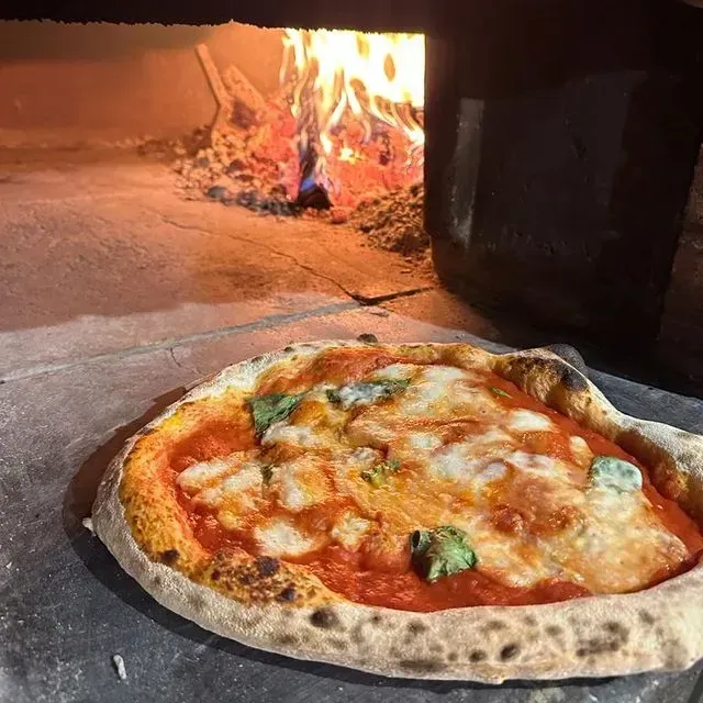Una pizza está sobre una mesa frente a un horno.