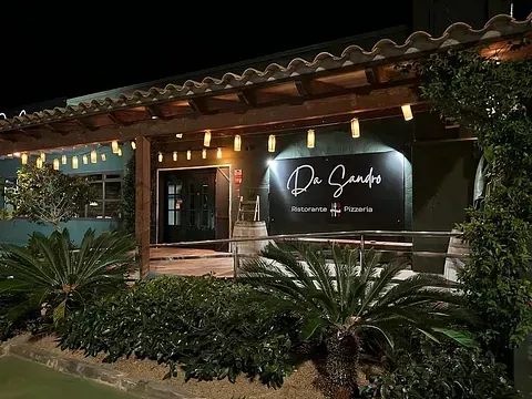 Un restaurante con un cartel al costado está iluminado por la noche.
