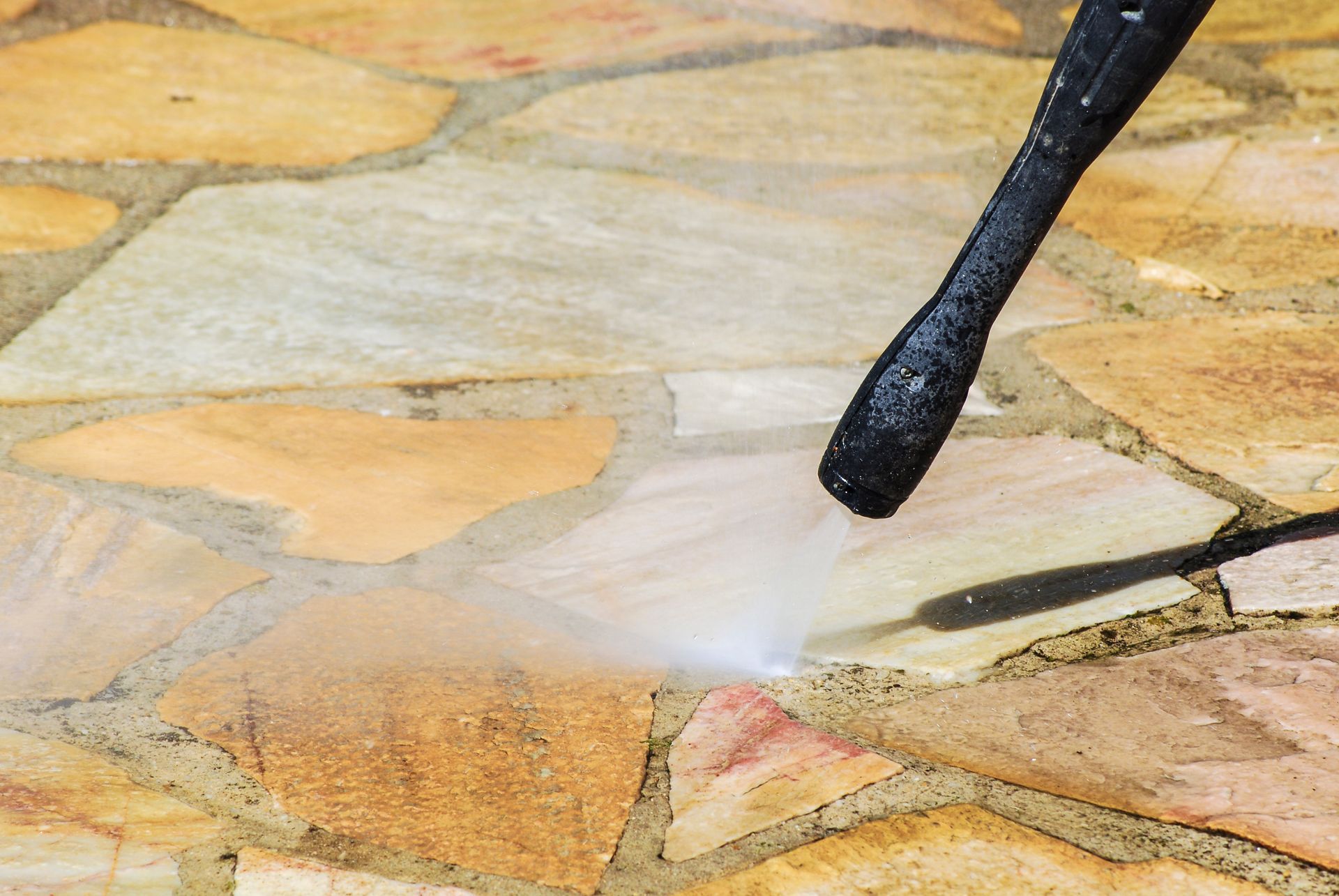 Nettoyeur à haute pression utilisé sur un patio en pierre, nettoyant la surface.