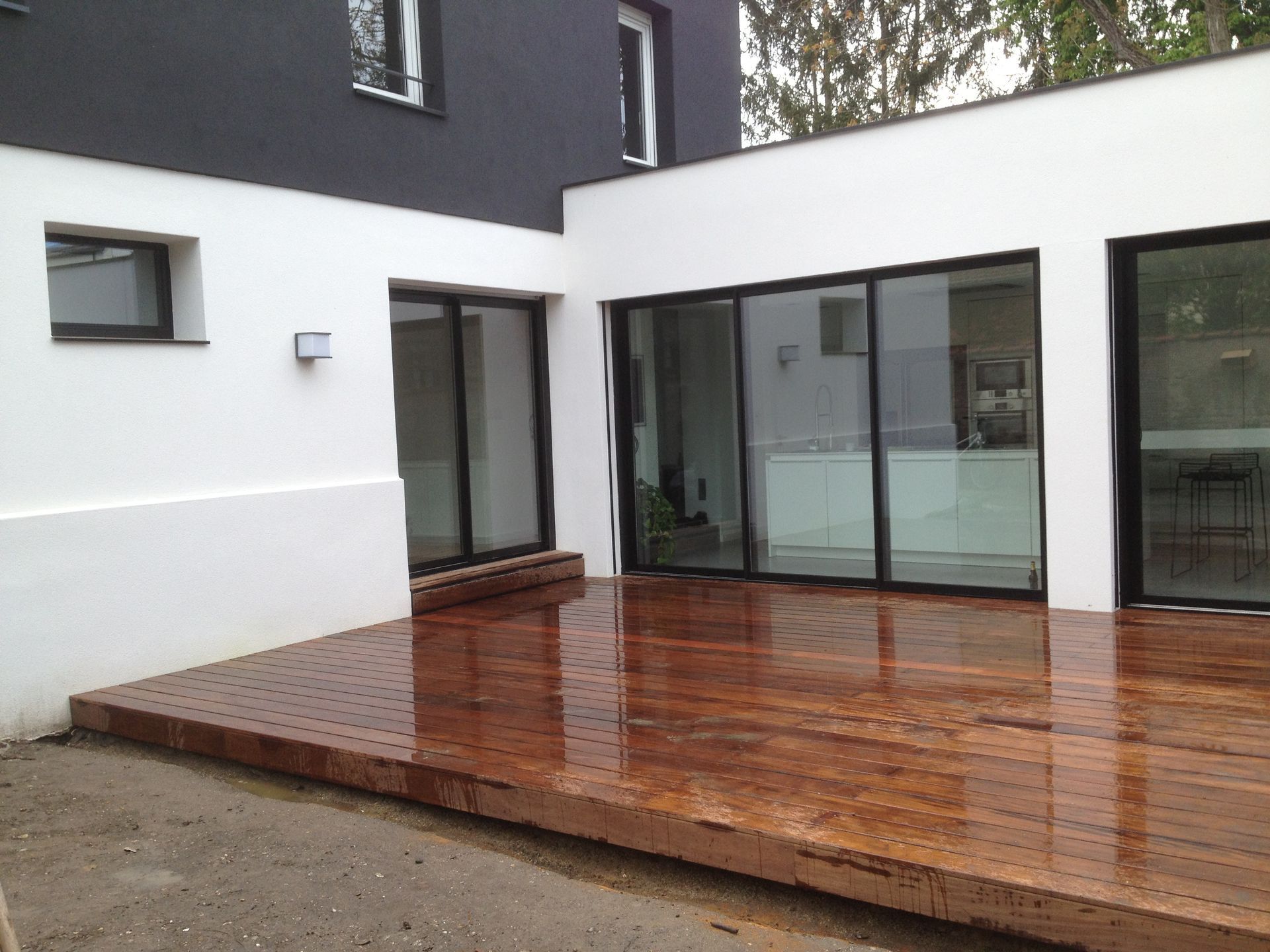 Terrasse en bois exotique Ipé devant une maison contemporaine avec baies vitrées